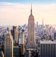 View of the Empire State Building rising above the New York City skyline at sunset.
