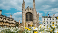 Historic university buildings and chapel architecture on the Cambridge campus surrounded by flowers.