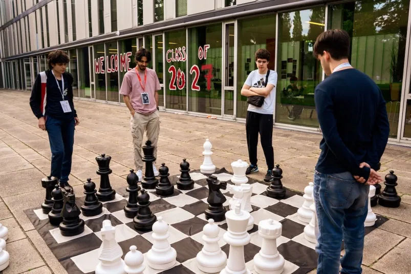 Students playing a life-sized outdoor chess game in front of a university building.
