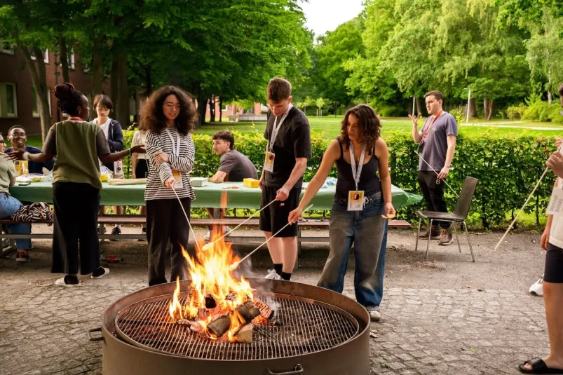 Students gathered around an outdoor fire pit during a social activity on campus.