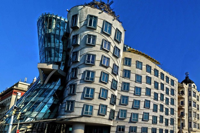 Modern architectural landmark in Prague featuring a curved concrete-and-glass building with distinctive asymmetrical design under a clear blue sky.